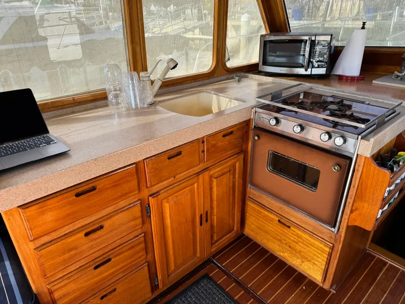 1979 Californian LRC Sedan Bridge kitchen with wooden cabinets, stove, and countertop appliances.