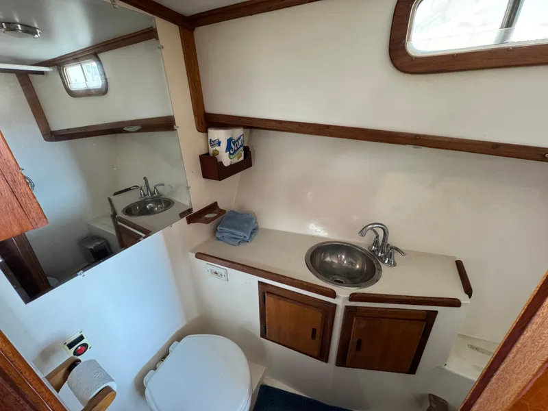 1979 Californian LRC Sedan Bridge bathroom with sink, toilet, and wooden cabinets.