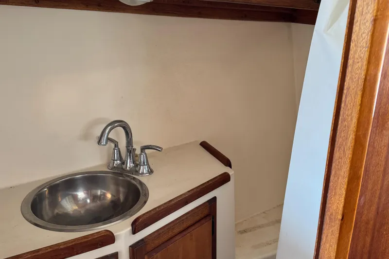 1979 Californian LRC Sedan Bridge bathroom sink with wooden accents and stainless steel faucet.
