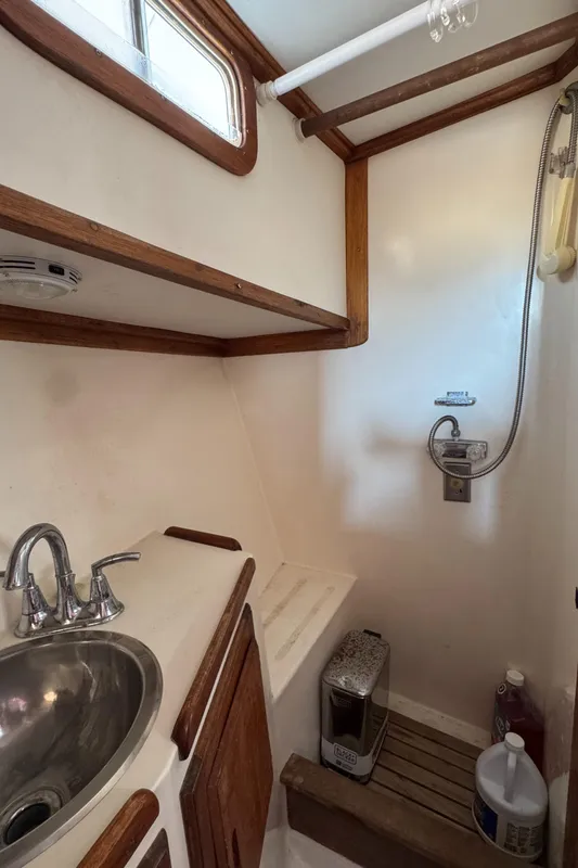 1979 Californian LRC Sedan Bridge bathroom with sink, shower, and wooden accents.