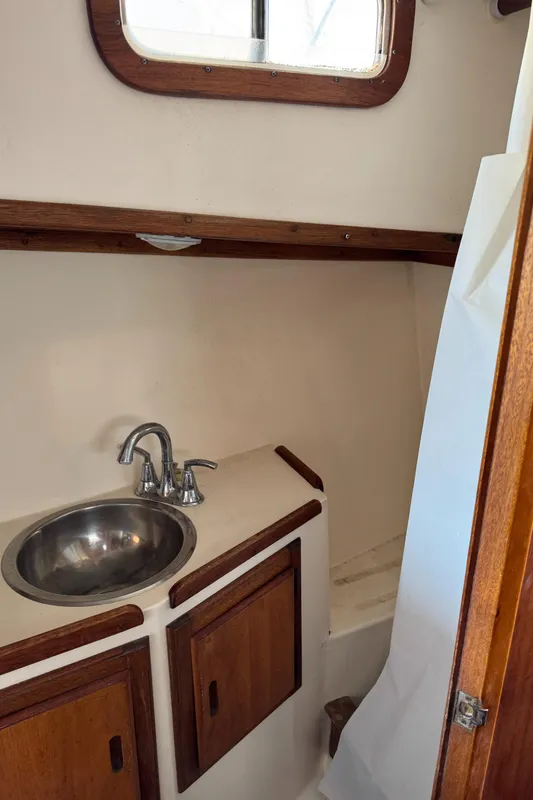 1979 Californian LRC Sedan Bridge bathroom with sink, wooden cabinets, and window.
