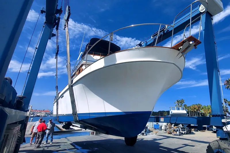 1979 Californian LRC Sedan Bridge yacht being lifted at a marina under a clear blue sky.