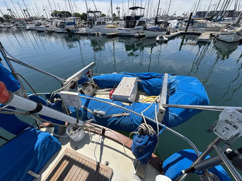 Sailboat docked in marina with blue covers, CAL 246 model, 1973.