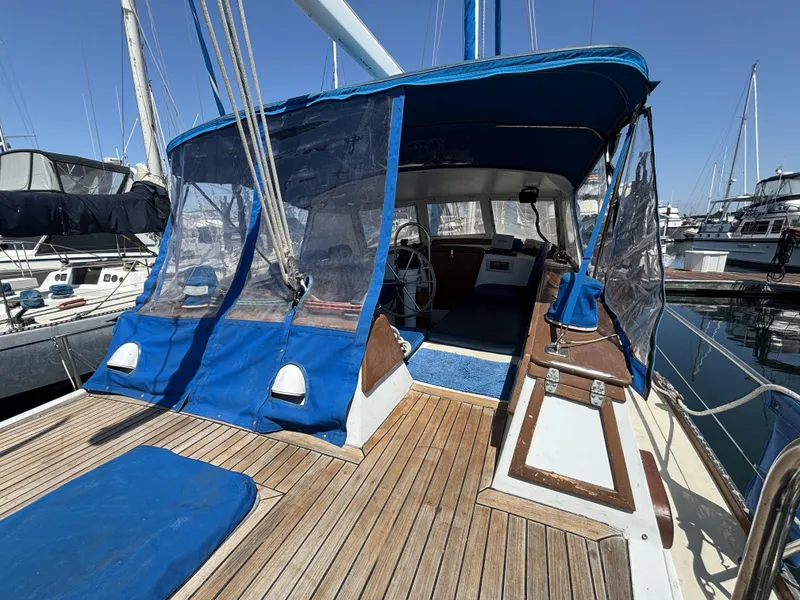 1973 CAL 246 sailboat with blue canopy and wooden deck in marina.