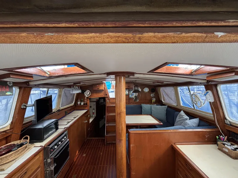 Interior of a 1973 CAL 246 sailboat with wood finishes and cozy seating area.