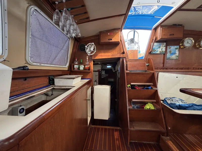 Interior of a 1973 CAL 246 sailboat with wooden cabinetry and nautical decor.