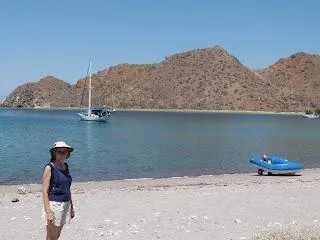 Woman on beach with sailboat and hills in background, CAL 246, 1973.