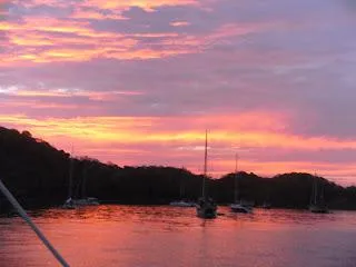 Sailboats silhouetted against a vibrant sunset over calm waters, CAL 246, 1973.