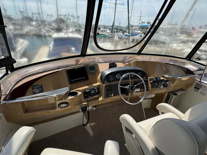 2004 Carver 366 Motor Yacht helm with steering wheel, controls, and marina view.