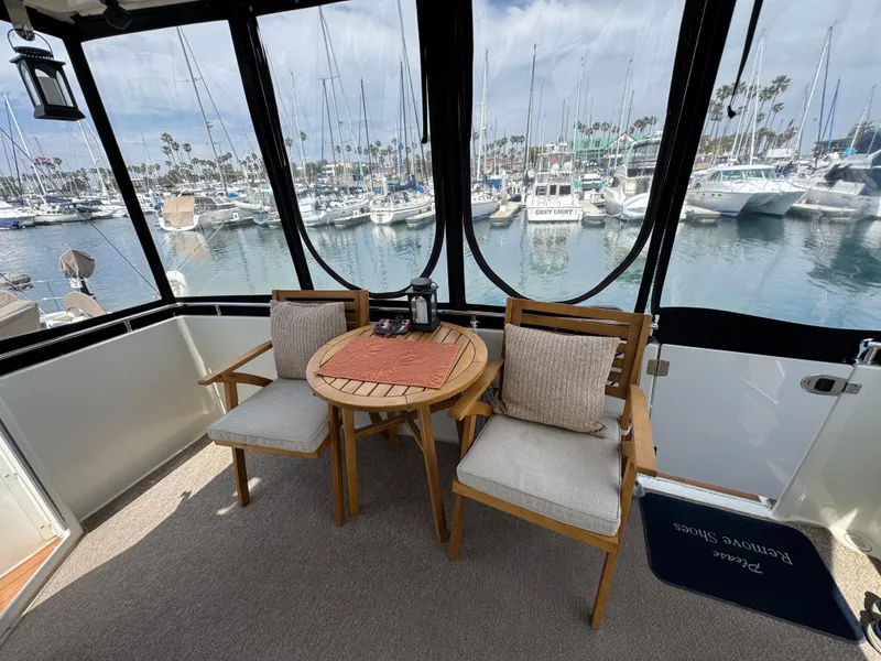 2004 Carver 366 Motor Yacht interior with wooden chairs and table, overlooking marina.