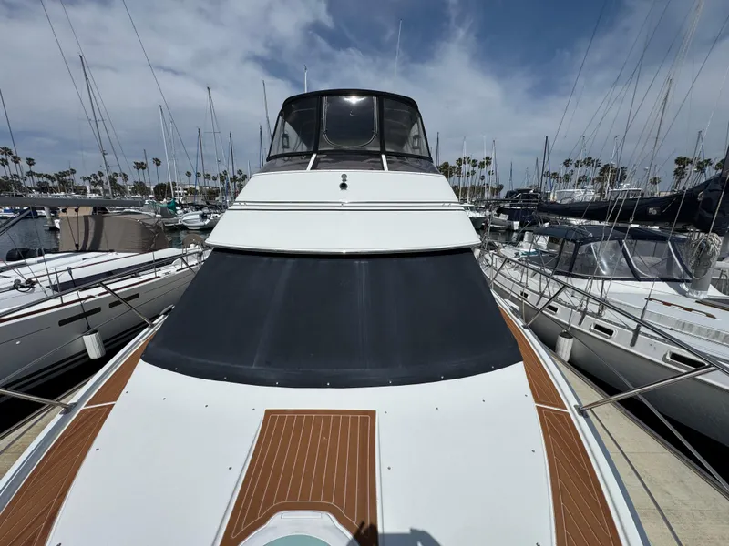 2004 Carver 366 Motor Yacht docked at marina, surrounded by sailboats under a partly cloudy sky.