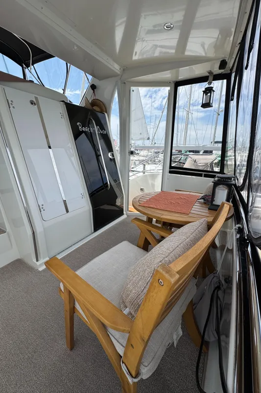 2004 Carver 366 Motor Yacht interior with wooden chairs and table, overlooking marina.