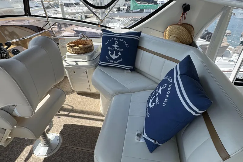 2004 Carver 366 Motor Yacht interior with white seating, nautical pillows, and marina view.