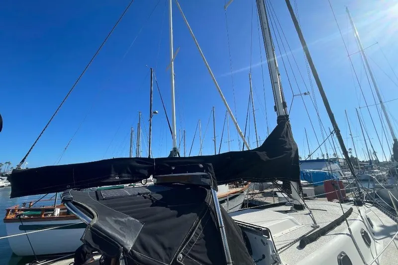 Sailboat Custom Bodega 30, 1977 model, docked in marina under clear blue sky.