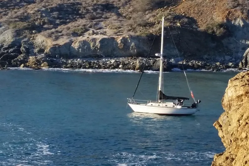 Sailboat "Bodega 30" from 1977 anchored near rocky coastline.