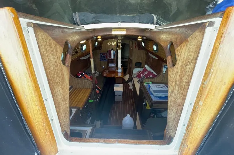 Interior view of a 1977 Custom Bodega 30 sailboat, featuring wooden finishes and compact design.