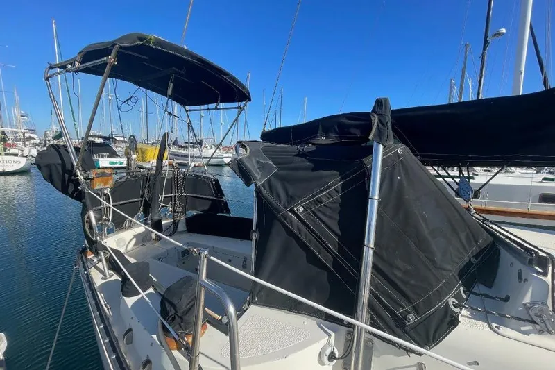 1977 Custom Bodega 30 sailboat with black canopy docked in marina.