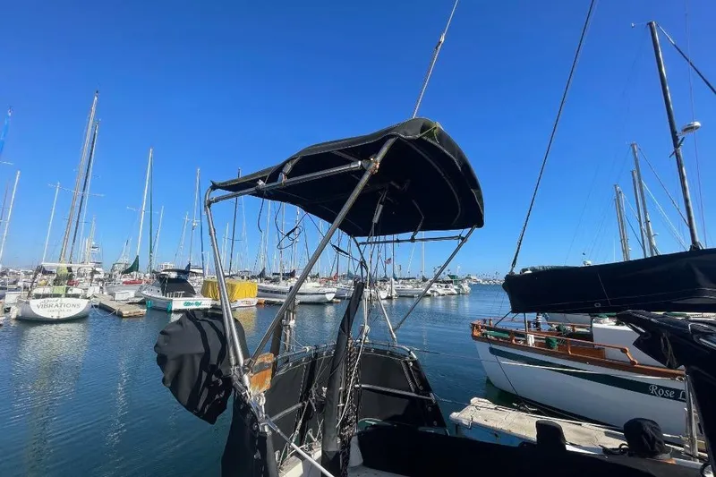 Sailboats docked at a marina under clear blue skies, featuring a 1977 Custom Bodega 30.