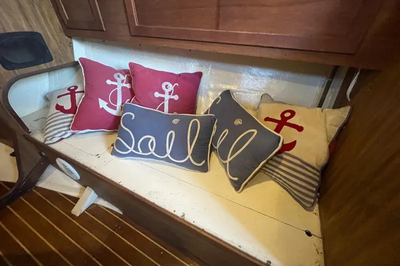 Nautical-themed cushions on a wooden bench inside a 1977 Custom Bodega 30 boat.
