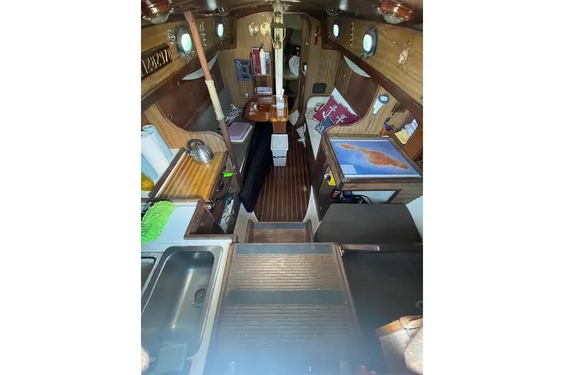 Interior of 1977 Custom Bodega 30 sailboat with wooden finishes and nautical decor.