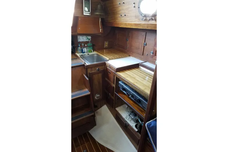 1977 Custom Bodega 30 yacht interior with wooden cabinetry and compact kitchen area.