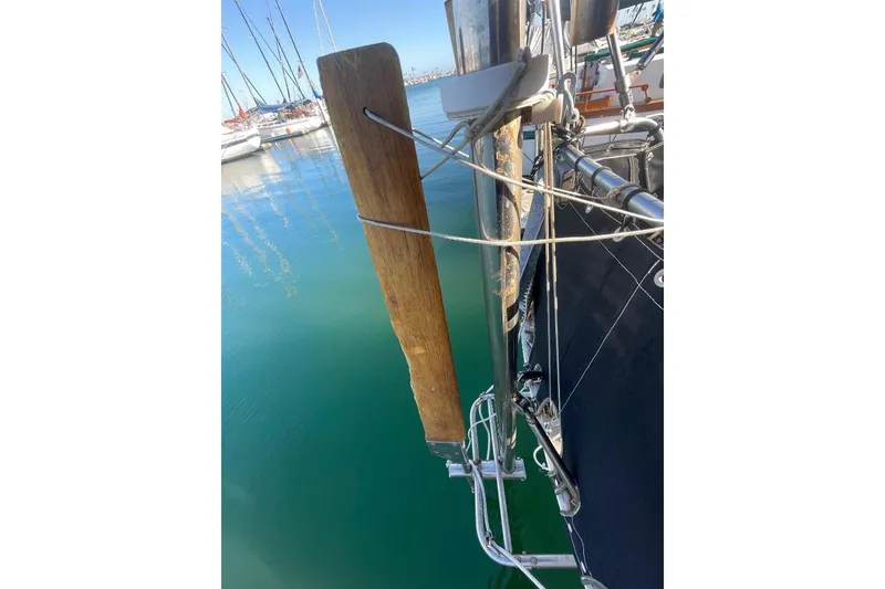 Custom Bodega 30 sailboat detail, 1977 model, docked in a marina with clear water.