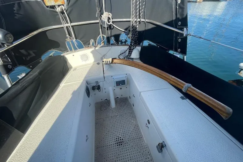 Cockpit of 1977 Custom Bodega 30 sailboat with wooden tiller and nautical equipment.
