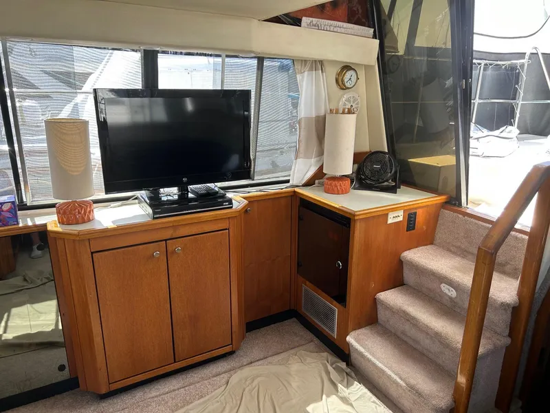 Interior of 1994 Bayliner 4587 Motoryacht with TV, wooden cabinets, and carpeted stairs.