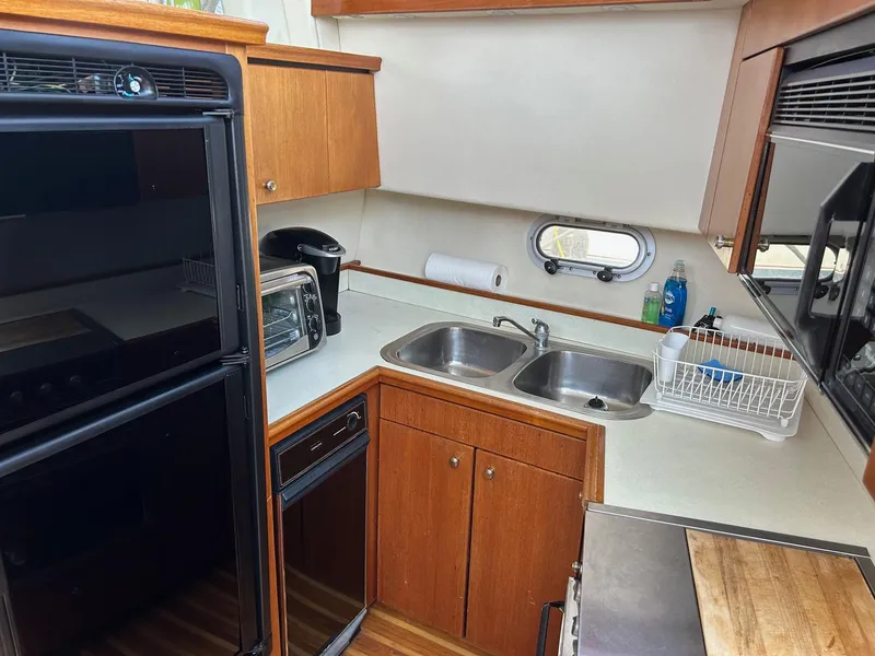 1994 Bayliner 4587 Motoryacht kitchen with dual sinks, appliances, and wood cabinetry.
