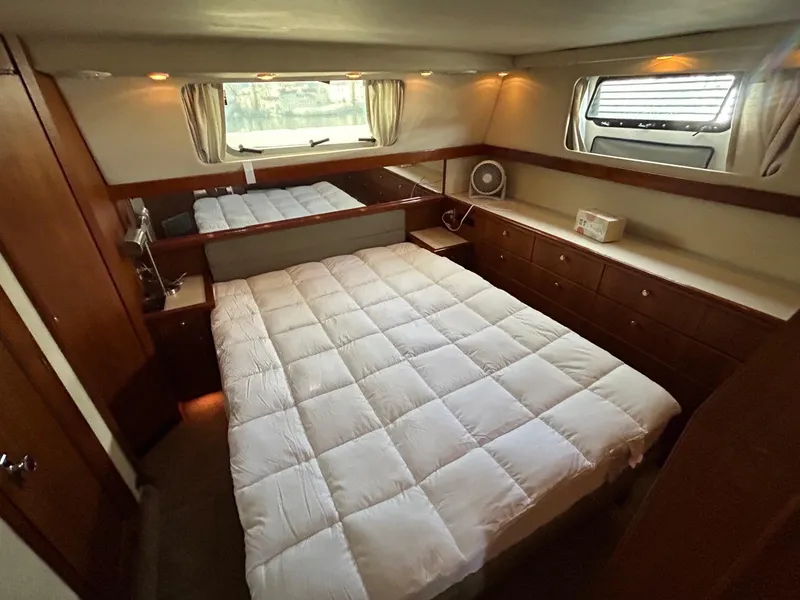 Luxurious bedroom in 1994 Bayliner 4587 Motoryacht with cozy bedding and wooden cabinetry.