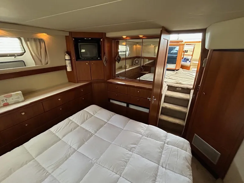 Luxurious bedroom interior of 1994 Bayliner 4587 Motoryacht with wood cabinetry and cozy bedding.