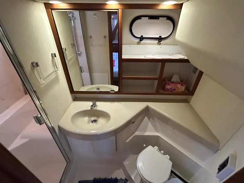 1994 Bayliner 4587 Motoryacht bathroom with sink, toilet, mirror, and storage shelves.