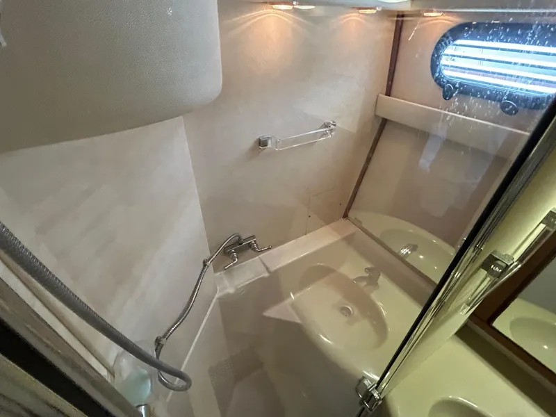 1994 Bayliner 4587 Motoryacht bathroom with shower, sink, and porthole window.