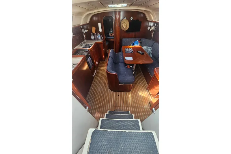 Interior of 1996 Beneteau Oceanis 440 sailboat with wooden flooring and cozy seating area.