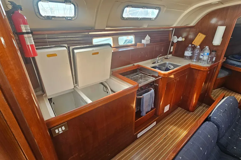 Interior of 1996 Beneteau Oceanis 440 yacht kitchen with wood finish and appliances.