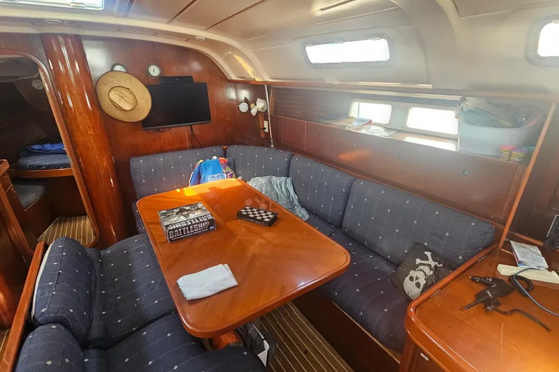 Cozy interior of 1996 Beneteau Oceanis 440 sailboat with wooden furnishings and seating area.