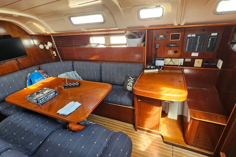 Cozy interior of 1996 Beneteau Oceanis 440 sailboat with wooden furnishings and seating area.