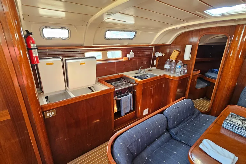 Interior of 1996 Beneteau Oceanis 440 yacht with wooden cabinetry and cozy seating area.