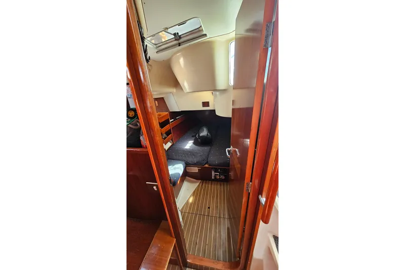 Interior cabin of 1996 Beneteau Oceanis 440 sailboat, featuring wooden finishes and cozy sleeping area.
