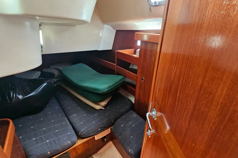 Interior cabin of 1996 Beneteau Oceanis 440 sailboat with wooden finish and cushions.