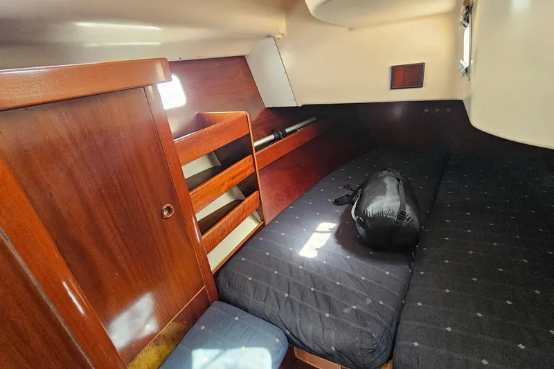 Interior cabin of 1996 Beneteau Oceanis 440 sailboat with wooden finish and cozy bedding.