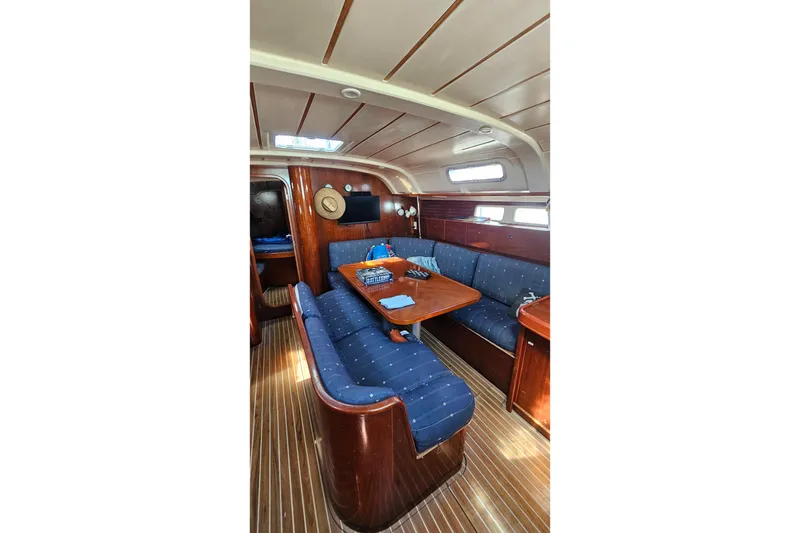 Interior of 1996 Beneteau Oceanis 440 yacht with blue seating and wooden table.