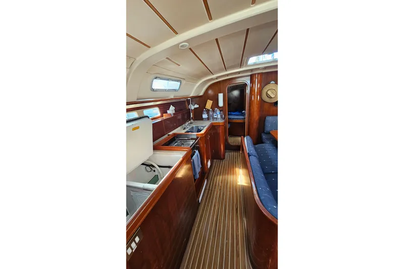 Interior of 1996 Beneteau Oceanis 440 yacht with wooden cabinetry and seating area.