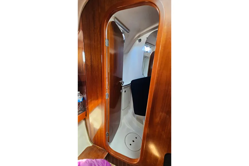 Interior view of 1996 Beneteau Oceanis 440 sailboat, featuring wooden door and cabin details.