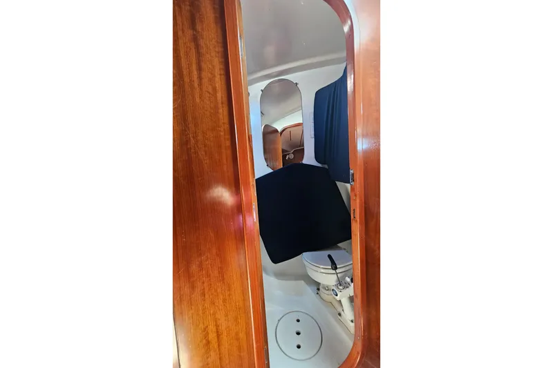 Interior view of 1996 Beneteau Oceanis 440 yacht bathroom with wooden door and marine toilet.
