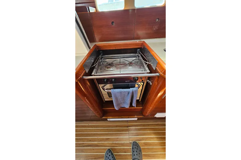 Galley stove in 1996 Beneteau Oceanis 440 yacht interior, featuring wooden cabinetry.