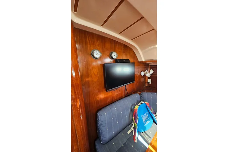 Interior of 1996 Beneteau Oceanis 440 yacht with wood paneling and mounted TV.