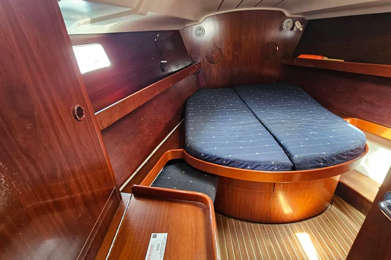 Cozy cabin interior of 1996 Beneteau Oceanis 440 sailboat with wooden finish and double bed.