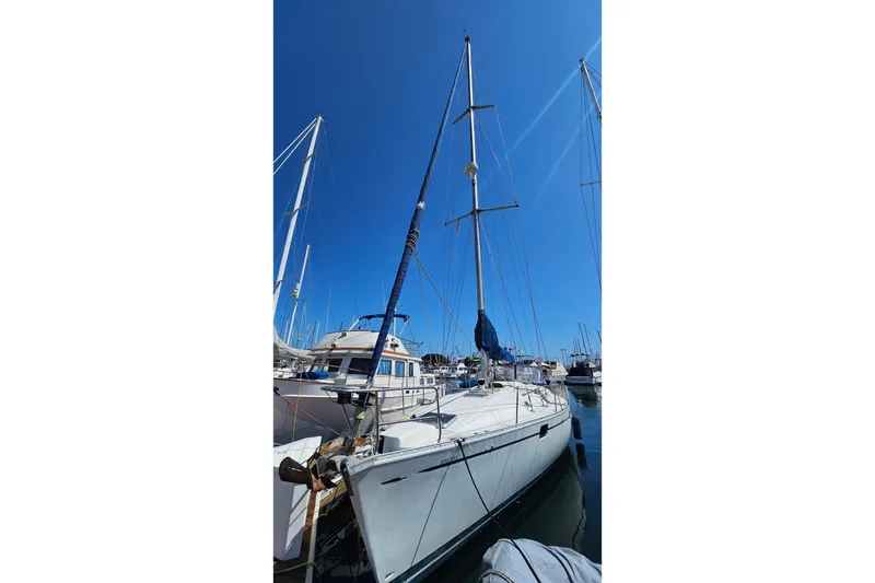 Sailboat Beneteau Oceanis 440, 1996 model, docked in a marina under clear blue sky.