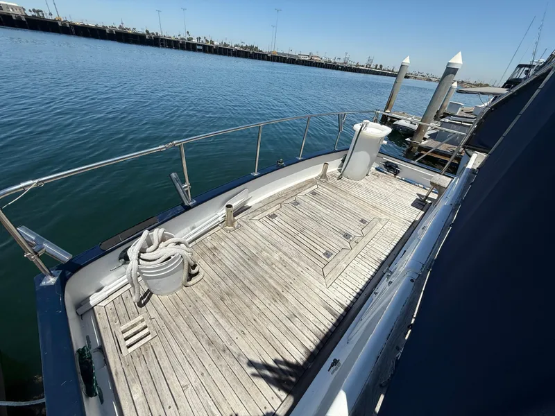 1981 DeFever Passagemaker yacht deck with wooden flooring, docked at a marina.
